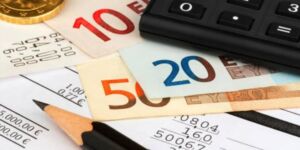 أوراق نقدية من فئة 20 و 10 و50 يورو وألة حاسبة وأوراق يتم فيها حساب  نسبة الضرائب في ألمانيا