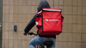 عامل توصيل على دراجة هوائية يحمل صندوق دور داش DoorDash لتوصيل الطعام